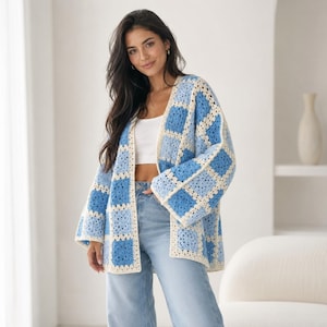 Peut inclure: Un cardigan ouvert à manches longues composé de carrés de crochet dans des tons variés de bleu et de crème. Le vêtement présente une silhouette carrée avec des manches larges et un motif géométrique répétitif sur toute la structure.