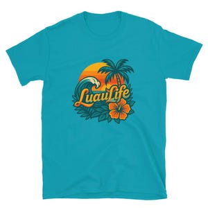 Puede incluir: Camiseta turquesa con un diseño tropical "Luau Life". El gráfico incluye una puesta de sol, una palmera, una ola del océano y una flor de hibisco. El diseño utiliza colores naranja, amarillo, verde y blanco.