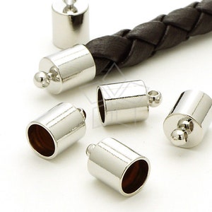 Puede incluir: Cinco tapones de metal plateado para cordón o cuerda de cuero. Los tapones tienen una abertura redonda y una pequeña bola en el extremo.