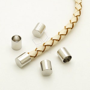 May include: Five silver metal end caps for leather cord or rope. The end caps are cylindrical and have a smooth, polished finish.