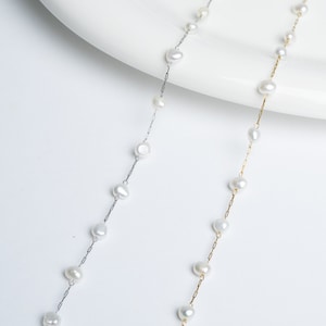 May include: Two delicate necklaces with a silver and gold chain, each adorned with a row of white pearl beads.