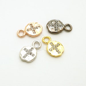 May include: Four silver, gold, rose gold, and gunmetal charms with a cross design encrusted with clear rhinestones. Each charm has a small loop for attaching to jewelry.