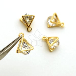 May include: Four gold-tone triangle-shaped charms with clear crystal accents. Each charm has a loop for attaching to jewelry.