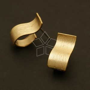 May include: A pair of gold-toned earrings with a textured, wavy design. The earrings are made of metal and have a brushed finish.