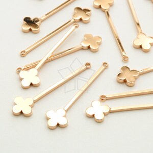 May include: Gold-toned metal flower charms with a four-leaf clover design attached to a straight metal bar. The charms are perfect for jewelry making and crafting.