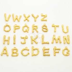 Könnte beinhalten: Goldfarbene Metall-Anhänger in Form von Zweigen mit den Buchstaben des Alphabets. Die Buchstaben sind von A bis Z.