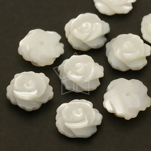 May include: Ten white mother of pearl flower shaped beads. The beads are carved to resemble roses.