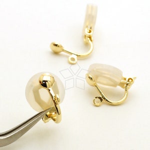 May include: A pair of gold-tone clip-on earrings with clear, round, plastic stones. The earrings have a simple, elegant design.