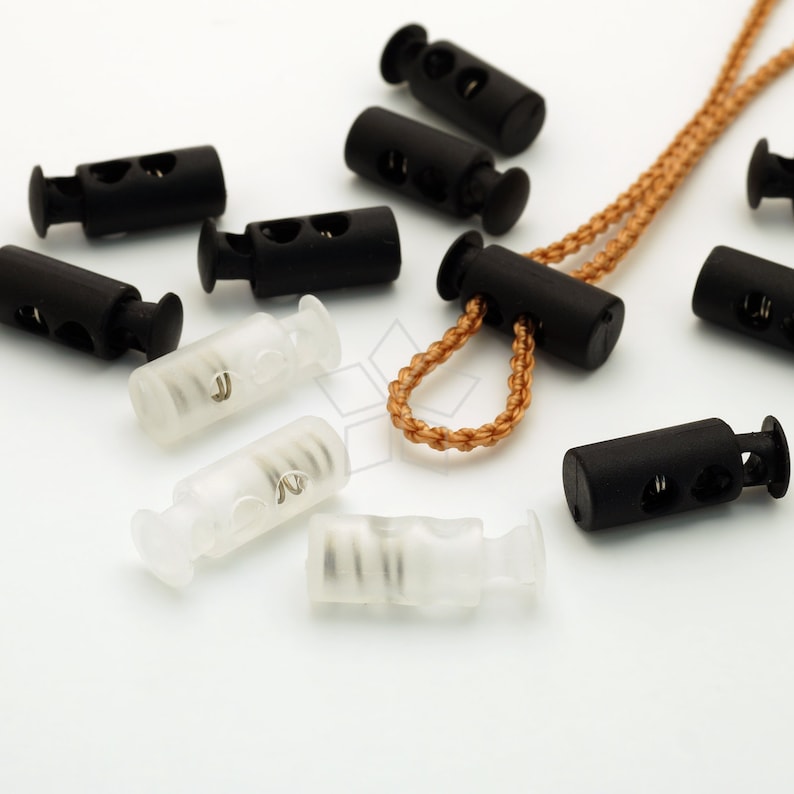 May include: Assortment of black and clear plastic cord locks with a spring mechanism. The cord locks are used for adjusting the length of cords and straps.