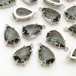 May include: A group of silver teardrop-shaped pendants with clear gray faceted glass stones. The pendants have a loop at the top for attaching to jewelry.