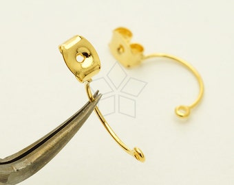 May include: Gold-toned earring findings with a curved wire and a small, flat, round piece with a hole in the center. The findings are being held by a pair of pliers.