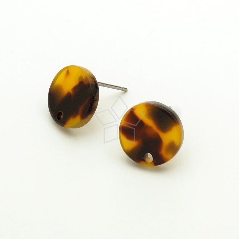 May include: A pair of brown and yellow tortoiseshell stud earrings with a small hole in the centre of each earring.