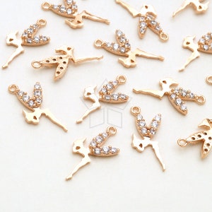 May include: Gold-toned metal fairy charms with clear crystal accents. Each charm features a fairy design with outstretched arms and a loop for attaching to jewelry or other crafts. The charms are scattered across a white surface.