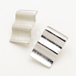 Könnte beinhalten: Ein Paar silberne Ohrringe mit einem wellenförmigen, strukturierten Design. Die Ohrringe sind rechteckig und haben eine gebürstete Oberfläche.