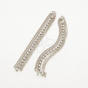 May include: A pair of silver dangle earrings with multiple chains adorned with clear rhinestones.