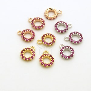 Może przedstawiać: Zestaw okrągłych zawieszek w kolorze złotym, różowego złota i srebrnym z pierścieniem z różowych cyrkonii. Każda zawieszka ma małą pętelkę do mocowania do biżuterii.