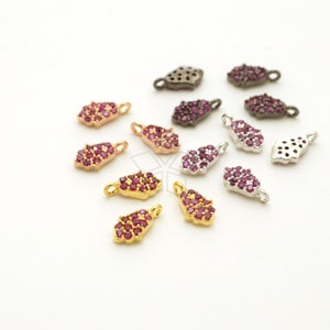 May include: A collection of small, decorative charms in various metallic finishes, including gold, silver, and gunmetal. Each charm features a cluster of small, round, ruby-colored gemstones. The charms are designed with a loop for attaching to jewelry.