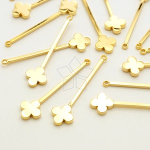 May include: Gold-toned metal flower charms with a loop at the top and a straight metal rod extending from the bottom. The charms are scattered on a white surface.