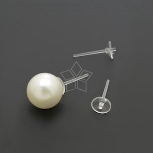 May include: A white pearl earring with a clear plastic post and butterfly back.