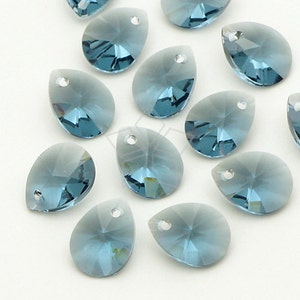 May include: Close-up of several teardrop-shaped, faceted blue crystal beads. Each bead has a small hole at the top for stringing. The crystals have a gradient effect, transitioning from a lighter blue to a deeper shade.