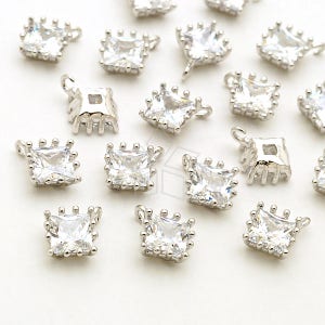 May include: A group of silver-toned square pendant charms with clear crystal accents. Each charm has a loop at the top for attaching to a necklace or bracelet.