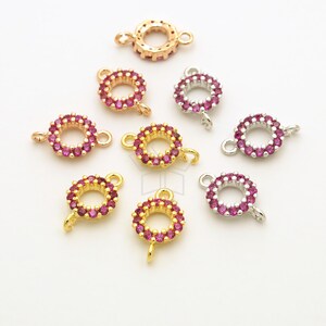 May include: Assortment of gold, silver, and rose gold jump rings with a circle of pink rhinestones around the ring. The jump rings have a small loop on one side and a larger loop on the other side.