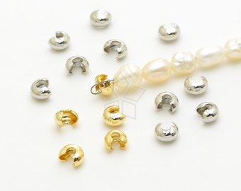 May include: A close-up of a variety of gold and silver crimp beads. The beads are small and round, with a hole in the center. They are used to secure jewelry findings, such as clasps and charms.