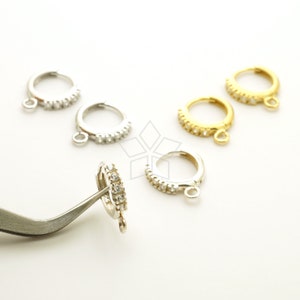 May include: Five pairs of hoop earrings with a row of clear cubic zirconia stones. The earrings are available in silver and gold.