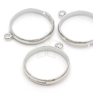 May include: Three silver metal ring blanks with a jump ring attached to each. The ring blanks are round and have a smooth finish.