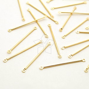 May include: A collection of gold-colored metal jump rings with a straight bar and two loops at each end. The jump rings are scattered on a white surface.
