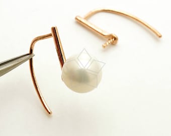 May include: A pair of rose gold earrings with a single white pearl on each earring. The earrings have a simple, modern design.