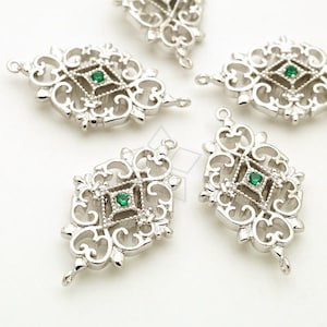 May include: Five silver filigree charms with green gemstone accents. Each charm features a square-shaped design with intricate details.