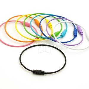 May include: Assortment of colorful key rings made of braided metal cable with a metal clasp. The key rings are in various colors, including pink, orange, yellow, green, blue, purple, and white. One black key ring is also shown.