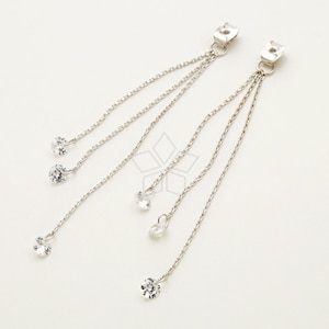 May include: A pair of silver clip-on earrings with three dangling chains and clear crystal accents.