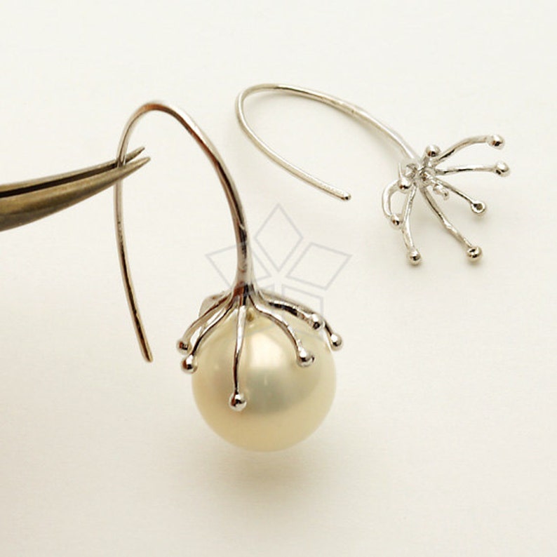 Op de afbeelding: Een paar zilveren oorbellen met een parel en een delicaat, vertakt ontwerp. De oorbellen zijn gemaakt van zilver en hebben een eenvoudige, elegante stijl.