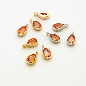 May include: Assortment of teardrop-shaped pendants with orange crystal accents. The pendants are made of gold, silver, and rose gold metal.