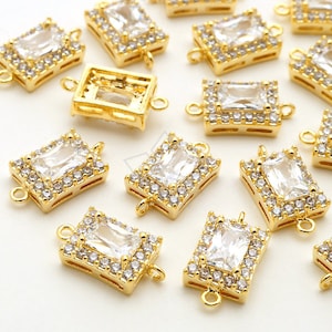 May include: Gold-tone metal connector charms with a clear rectangular crystal surrounded by smaller clear crystals. The charms have a loop on each end for attaching to jewelry.