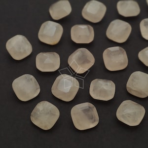 Op de afbeelding: Een verzameling van 16 doorschijnende, lichtroze, vierkante edelsteen cabochons. De cabochons zijn gefacetteerd en hebben een gladde, gepolijste afwerking.