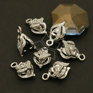 Puede incluir: Encantos de colgante de metal plateado en forma de flor con acentos de cristal transparente. Los encantos tienen un bucle en la parte superior para sujetar a las joyas.