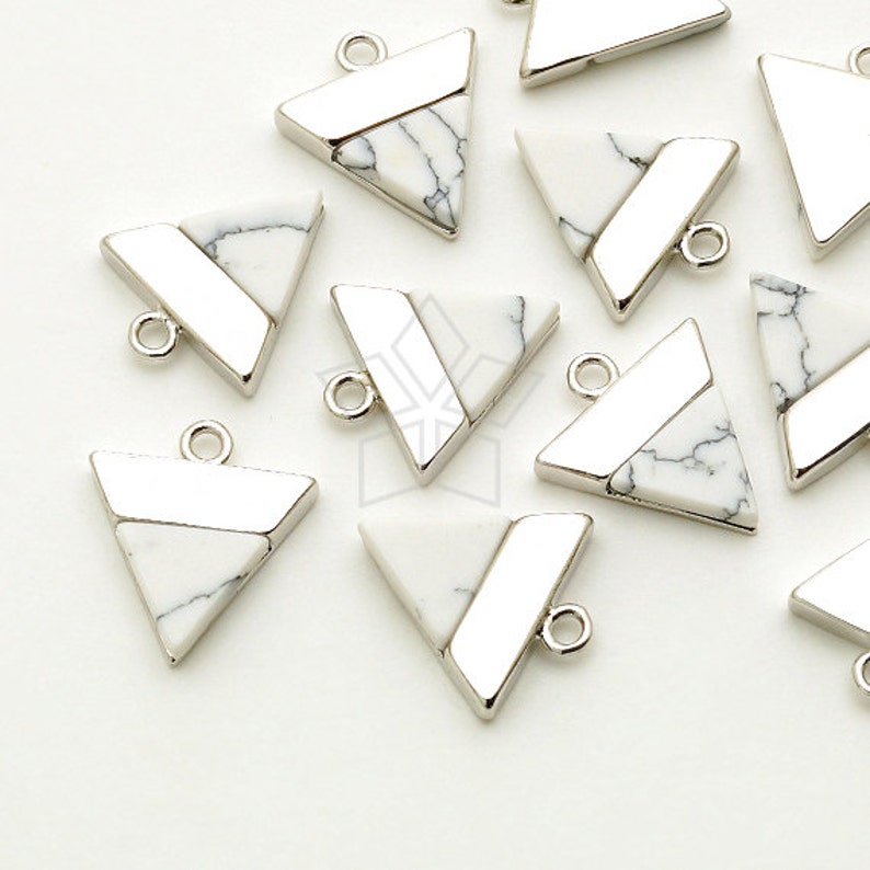 May include: Geometric triangle pendants with a white and black marbled stone inlay and a silver-tone metal frame. Each pendant has a small loop for attaching to a chain or other jewelry component. The pendants are ideal for DIY jewelry making.