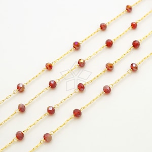 Op de afbeelding: Close-up van verschillende strengen goudkleurige ketting versierd met facetgeslepen, rood-oranje kralen. De kralen zijn gelijkmatig verdeeld over de kettingen, wat een delicaat en elegant ontwerp creëert. De kettingen staan tegen een witte achtergrond.