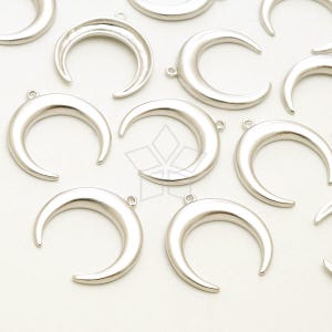 Puede incluir: Un grupo de dijes de media luna plateados con un agujero en la parte superior para sujetarlos a joyas u otras manualidades.