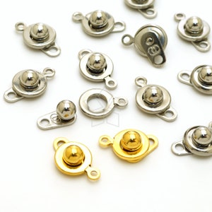 May include: Assortment of silver and gold metal clasps with ball closures. The clasps are designed for attaching fabric or leather pieces together.