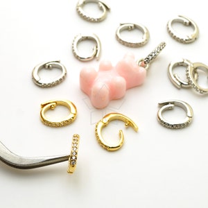 Op de afbeelding: Een roze gummy bear bedel met zilveren en gouden springringen. De springringen zijn versierd met kleine, heldere kristallen.