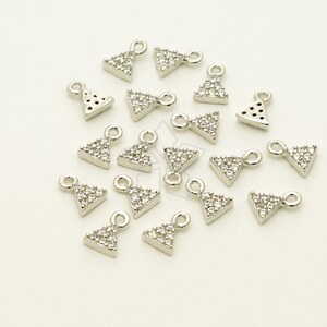 May include: A group of silver triangle charms with clear crystal embellishments. Each charm has a small loop for attaching to jewelry.