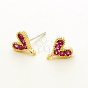 May include: A pair of gold heart-shaped earrings with pink gemstones. The earrings have a post and a hook closure.