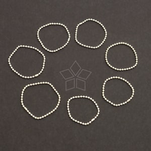 Peut inclure: Huit porte-clés en chaîne à billes argentées, formant chacun un cercle, sont disposés en cercle sur un fond noir.