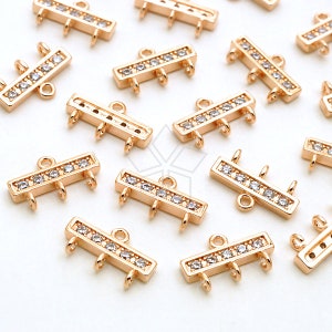 May include: Gold-tone metal connector with three loops and a row of clear rhinestones. The connector is rectangular in shape.