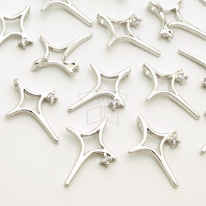 Puede incluir: Una colección de dijes de metal plateado en forma de estrellas con pequeños diamantes de imitación transparentes. Los dijes son perfectos para hacer joyas o para agregar un toque de brillo a las manualidades.