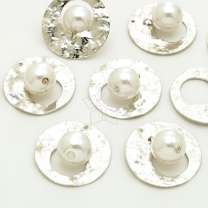 May include: A set of seven silver-toned metal circles with a hole at the top and a white pearl in the center. The circles have a hammered texture.